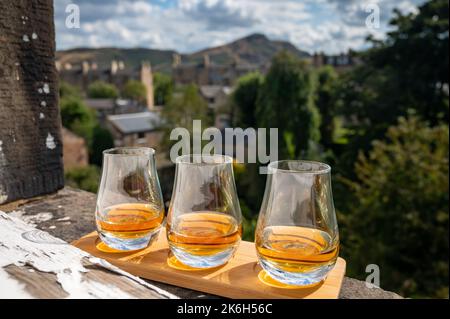 Flug von Single Malt Scotch Whisky serviert auf alten Fensterbank im Scottisch House mit Blick auf den alten Teil der Stadt Edinburgh und Hügel, Schottland, Großbritannien, DRAM Stockfoto