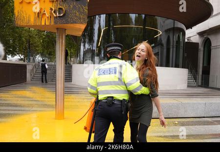 Polizisten verhaften einen Protestierenden von Just Stop Oil, nachdem sie vor dem New Scotland Yard in London ein Schild mit Sprühnebel besprüht hatte. Bilddatum: Freitag, 14. Oktober 2022. Stockfoto