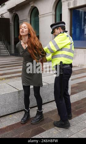 Polizisten verhaften einen Protestierenden von Just Stop Oil, nachdem sie vor dem New Scotland Yard in London ein Schild mit Sprühnebel besprüht hatte. Bilddatum: Freitag, 14. Oktober 2022. Stockfoto