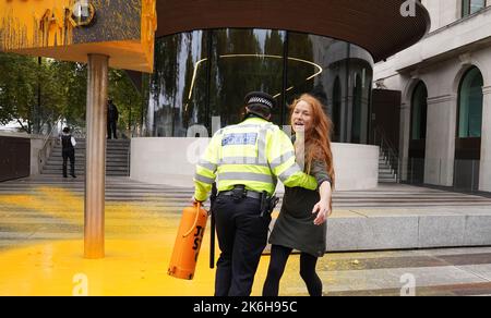 Polizisten verhaften einen Protestierenden von Just Stop Oil, nachdem sie vor dem New Scotland Yard in London ein Schild mit Sprühnebel besprüht hatte. Bilddatum: Freitag, 14. Oktober 2022. Stockfoto