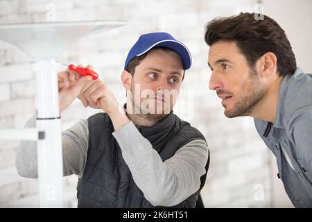 Der Handwerker überprüft den Lehrling, der Möbel in der Küche repariert Stockfoto