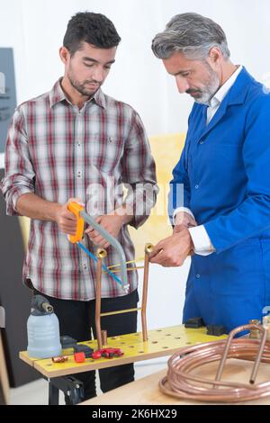 Klempner mit einer Metallsäge einige Rohre unten zu schneiden Stockfoto