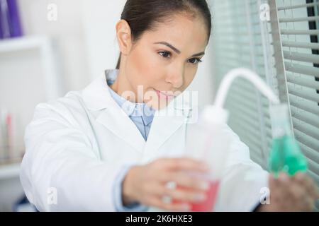 Ruhige junge Frau im Labor mit einem Pipettendispenser Stockfoto
