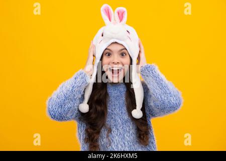 Bunny Winterhut. Ein erstaunlicher Teenager. Schöne Winter Kinder Porträt. Teenager Mädchen posiert mit Winter Pullover und Strickmütze auf gelbem Hintergrund. Aufgeregt Stockfoto