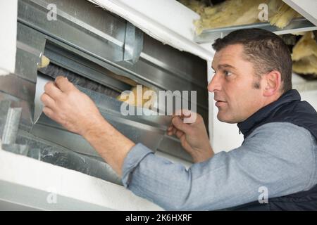 Arbeiter dämmen Steinwolle Isolierung in Metallrahmen Stockfoto