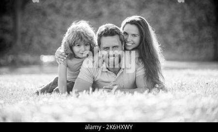 Adoption und Nächstenliebe. Familientag. Freundschaft. Vater Mutter und Kind auf grünem Parkgras. Stockfoto