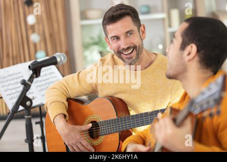 Gitarrelehrer unterrichtet seinen männlichen Klienten Stockfoto