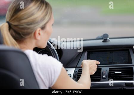 Frau schaltet die Klimaanlage im Auto Stockfoto