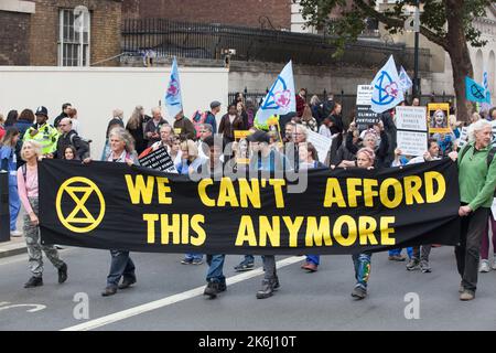 London, Großbritannien, 14. Oktober 2022: Extinction Rebellion marschiert Whitehall hinunter zur Downing Street, wo sie symbolisch Stromrechnungen verbrannten. Der Slogan des Protestes lautete: „Wir können uns das nicht leisten“, und bezog sich sowohl auf die Energiekosten in der Lebenshaltungskrise als auch auf die Klimakrise, die durch die Verbrennung fossiler Brennstoffe verursacht wurde. Auf den Postern wurde Liz Truss als Mitarbeiterin des Monats gezeigt, die ihre Verbindungen zur fossilen Energiewirtschaft hervorhob. Anna Watson/Alamy Live News Stockfoto