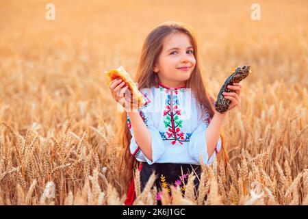 Bulgarisches Mädchen, schöne Frau, essen frisch gebackene Banitsa, Käsekuchen während der Ernte in goldenen Weizenfeld Stockfoto