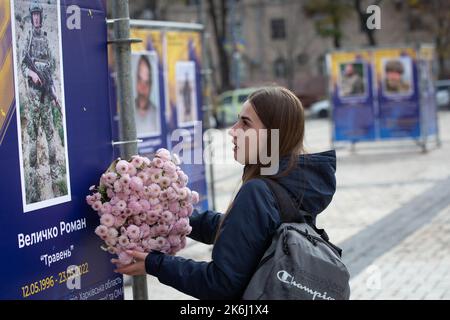 Ein Mädchen legt Blumen in die Straßenausstellung „Asow-Regiment - Engel von Mariupol“, die den Verteidigern der Einheit „Asow“ der Nationalgarde der Ukraine gewidmet ist, die bei der Verteidigung von Mariupol vor den russischen Invasoren in Kiew ums Leben gekommen sind. Russische Truppen sind am 24. Februar 2022 in die Ukraine eingedrungen und haben einen Konflikt ausgelöst, der Zerstörung und eine humanitäre Krise provoziert hat. (Foto von Oleksii Chumachenko / SOPA Images/Sipa USA) Stockfoto