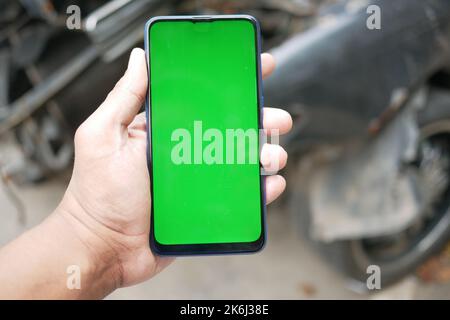 Mann, der ein Smartphone mit grünem Bildschirm für den Autoservice verwendet Stockfoto