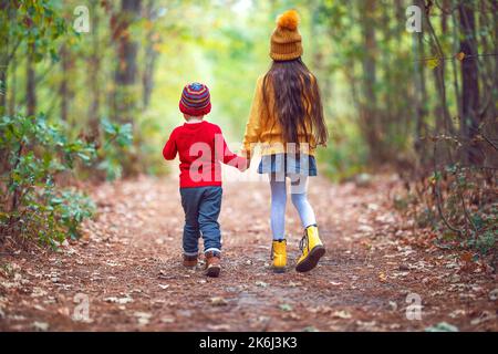 Glückliche Kinder im Wald genießen die Herbstsaison. Familie von Mädchen und Jungen, Bruder und Schwester spielen im Freien mit bunten Blätter fallen in Herbstwäldern. Stockfoto