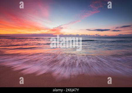 Wunderschöne Wolkenlandschaft über den Meereswellen und Strand über dem tropischen Inselstrand, Sonnenaufgang aufgenommen Stockfoto