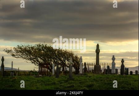 Ruinen der Doona-Kirche und der alte Friedhof in der Bucht von Tullaghan bei Sonnenuntergang. Stockfoto