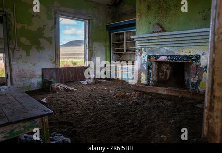 Verlassenes Haus. Es scheint, als hätten die Bewohner alles hinter sich gelassen, ohne zurückzuschauen. Das Haus ist mit einer dicken Schicht Schafsdung gefüllt. Stockfoto