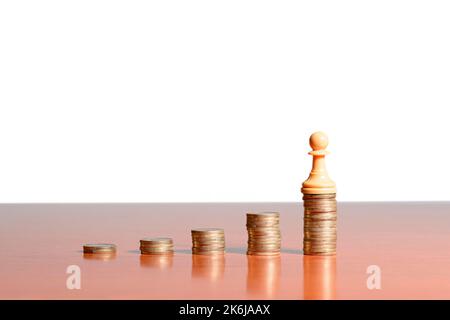 Schachfigur auf Münzen, die auf einem Holztisch mit weißem Hintergrund gestapelt sind. Konzept von persönlichem Erfolg, Unternehmertum und Unternehmensentwicklung. Stockfoto