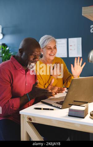 Ein vielseitiges Senior-Paar, das am Tisch sitzt und arbeitet Stockfoto