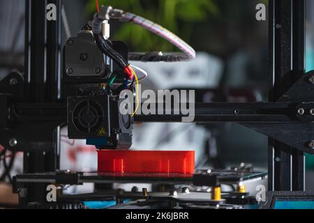 Elektronische dreidimensionale Kunststoff-Drucker während der Arbeit, 3D Drucker druckt rotes Modell, 3D Druck Stockfoto