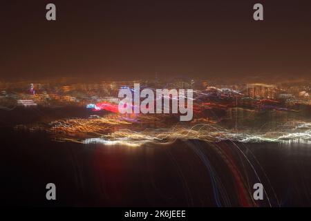 Nachtfoto der Stadt Doha aus einem Flugzeug. Kameraverschiebung für Effekt. Stockfoto