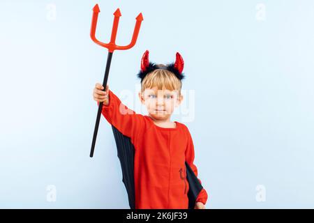 Niedlicher kleiner Junge im Teufel halloween Kostüm mit Hörnern und Dreizack Stockfoto