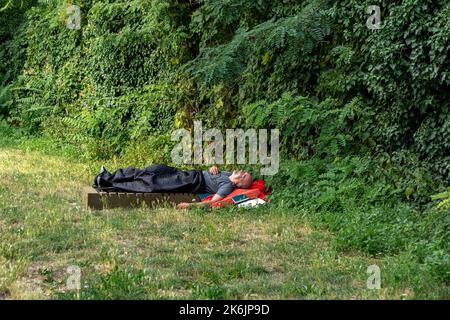 Berlin, Deutschland, Juli 21. Ein Obdachloser schläft am Abend des 21. Juli 2022 in Berlin unter freiem Himmel auf einer Schaumstoffmatratze auf dem Stadtplatz. Stockfoto