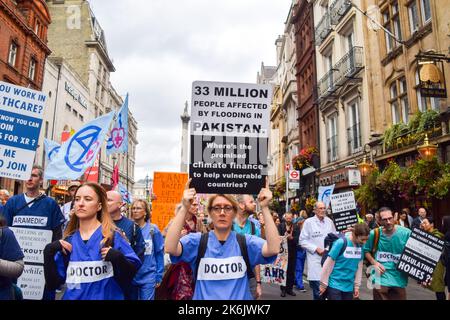 London, England, Großbritannien. 14. Oktober 2022. Ein Protestler, der in Whitehall marschiert, hält ein Plakat mit den Überschwemmungen in Pakistan. Die Demonstranten des Extinction Rebellion versammelten sich in Westminster und forderten Maßnahmen gegen die Klimakrise und explodierende Energiekosten. (Bild: © Vuk Valcic/ZUMA Press Wire) Stockfoto