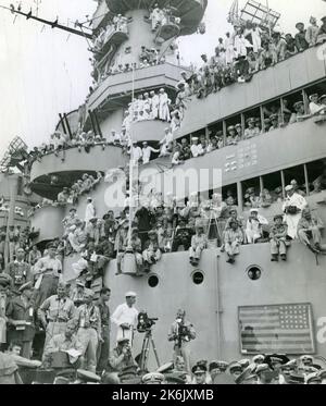 Zuschauer und Fotograf wählen Aussichtspunkte auf dem Deck der USS Missouri in der Bucht von Tokio, um die offizielle Kapitulation Japans am 2. September 1945 zu erleben Stockfoto