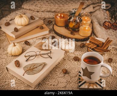 Ein Tischset für einen mit Kaffee oder einem magischen Elixier, auf einem gestrickten Tischtuch, mit Büchern zum Lesen und saisonalen Dekorationen Stockfoto