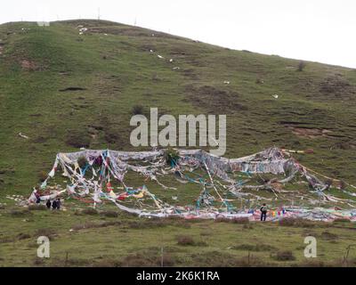 Buddhistische Gebetsfahnen, die von einem Fest übriggeblieben sind und regelmäßig im Buddhismus gezeigt werden, auf dem Hügel rund um das tibetische Kloster (Serti Gompa) in Langmusi. Sertri Gompa / Dacanglang Kloster (Dacanglangmu Saichisi). Eine berühmte Lamasery in Langmusi, Gansu, China. VRC. (126). Stockfoto