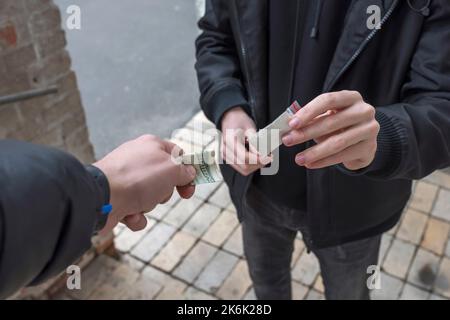 Ein Geldsüchtiger kauft eine Dosis von einem Händler auf der Straße. Suchtkonzept. Stockfoto