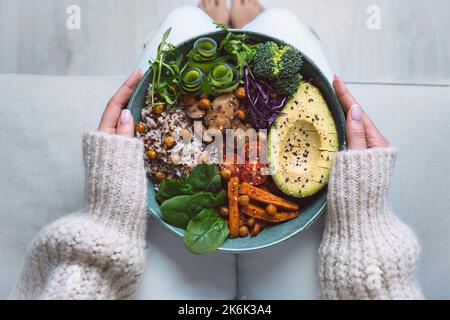 Gesunde Ernährung. Teller mit veganen oder vegetarischen Speisen in Frauenhand. Gesunde Ernährung auf pflanzlicher Basis. Gesundes Abendessen. Buddha Schüssel mit frischem Gemüse Stockfoto