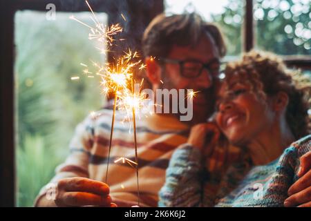Liebe und romantische Freizeitbeschäftigung mit Mann und Frau, die das Feuer funkelndes Licht zusammen halten und die Beziehung zu Hause auf einem Sofa genießen Stockfoto