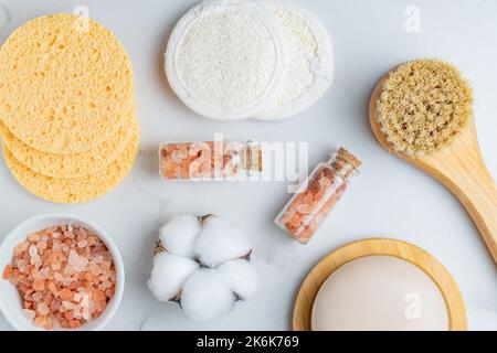 Persönliche Hygieneartikel und Kosmetika auf weißem Hintergrund. Gesichtsseife, Bürste mit natürlichen Borsten. Rosafarbenes himalaya-Salz in einer Bowla, Baumwolle und lufa-Rebusa Stockfoto