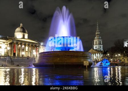 Beleuchteter Springbrunnen am Trafalgar Square bei Nacht, London England Großbritannien Stockfoto