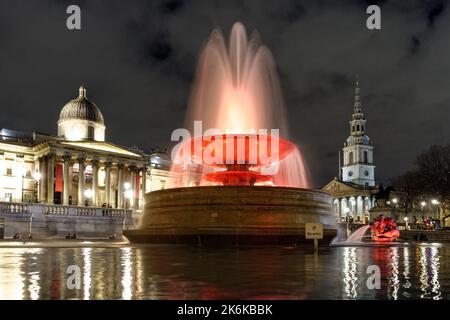 Beleuchteter Springbrunnen am Trafalgar Square bei Nacht, London England Großbritannien Stockfoto