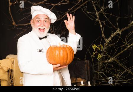 Koch in Chefuniform mit Kürbis zeigt Schild ok. Frohe halloween. Gesundes Produkt. Erntefest. Stockfoto