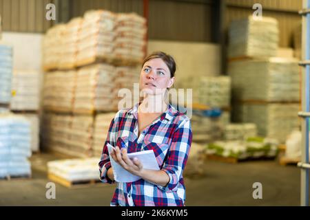 Frau, die im Lager steht und Dokumente in den Händen hält Stockfoto