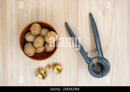 Haselnüsse in einer Schüssel mit einem Nussknacker daneben auf dem Tisch. Flach liegend. Stockfoto