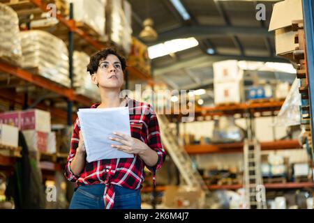 Die weibliche Lagerhalterin überprüft das Vorhandensein von Waren im Baustofflager Stockfoto