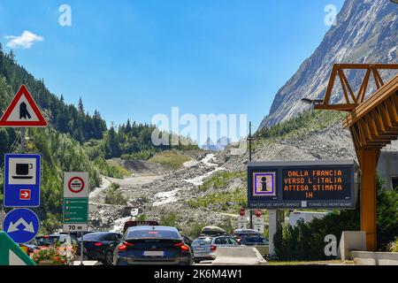 Elektronisches Schild mit Warnung vor der Wartezeit für den Mont Blanc-Tunnel von Frankreich nach Italien, mit Autos im Sommer aufgereiht, Courmayeur, italienische Grenze Stockfoto