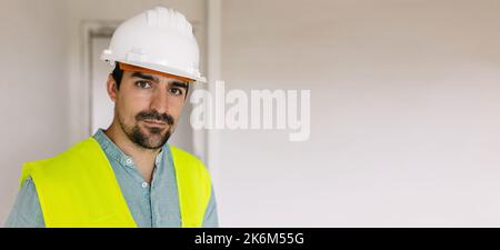 Porträt eines jungen Ingenieurs mit Schutzhelm, der in einem Gebäude steht Stockfoto
