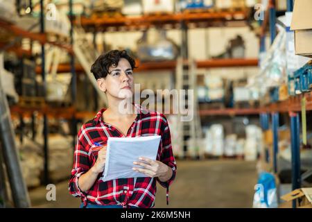 Die weibliche Lagerhalterin überprüft das Vorhandensein von Waren im Baustofflager Stockfoto