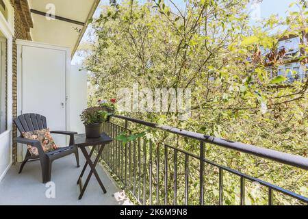 Balkon aus schmalen Ziegeln mit Metallgeländern, Holzstuhl und Tür Stockfoto