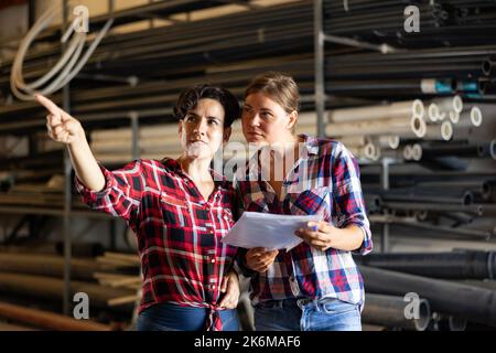 Der Manager sprach mit einer Mitarbeiterin im Lager und zeigte mit der Hand auf die Schachteln mit Produkten Stockfoto