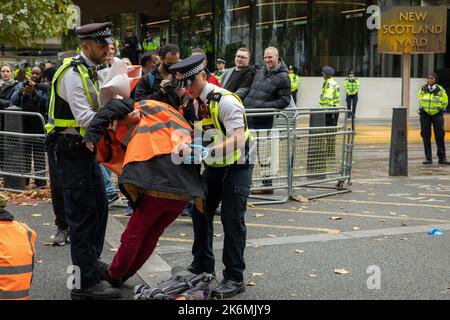 London, Großbritannien. 14.. Oktober 2022. Metropolitan Police Officers verhaften einen Klimaaktivisten von Just Stop Oil, der die Straße vor New Scotland Yard blockiert hatte, um die britische Regierung aufzufordern, die Erteilung von Öl- und Gaslizenzen einzustellen. Ein Aktivist besprühte auch das rotierende Schild von New Scotland Yard vor dem Gebäude mit gelber Farbe. Die Metropolitan Police nahm 24 Verhaftungen wegen des Verdachts der vorsätzlichen Behinderung der Autobahn und/oder der Verschwörung zur Begehung krimineller Schäden vor. Kredit: Mark Kerrison/Alamy Live Nachrichten Stockfoto