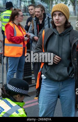London, Großbritannien. 14.. Oktober 2022. Ein Beamter der Metropolitan Police verhaftete einen Klimaaktivisten von Just Stop Oil, der die Straße vor New Scotland Yard blockiert hatte, um die britische Regierung aufzufordern, die Erteilung von Öl- und Gaslizenzen einzustellen. Ein Aktivist besprühte auch das rotierende Schild von New Scotland Yard vor dem Gebäude mit gelber Farbe. Die Metropolitan Police nahm 24 Verhaftungen wegen des Verdachts der vorsätzlichen Behinderung der Autobahn und/oder der Verschwörung zur Begehung krimineller Schäden vor. Kredit: Mark Kerrison/Alamy Live Nachrichten Stockfoto