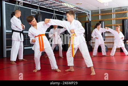 Zwei Jungen arbeiten zu zweit und meistern neue Karate-Bewegungen Stockfoto