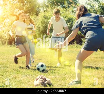 Jugendliche spielen im Sommer auf grünem Gras Fußball Stockfoto