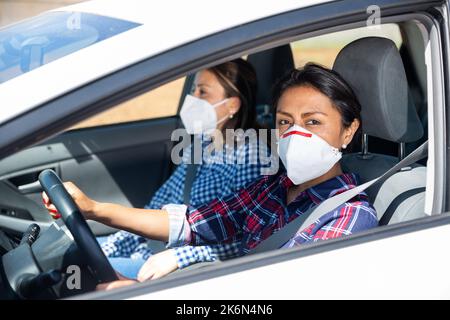 Zwei Frauen in Schutzmasken im Innenraum eines Autos Stockfoto